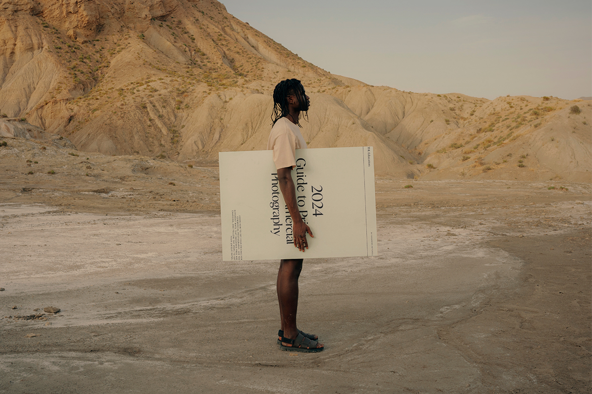 Man standing in the desert holding a poster.